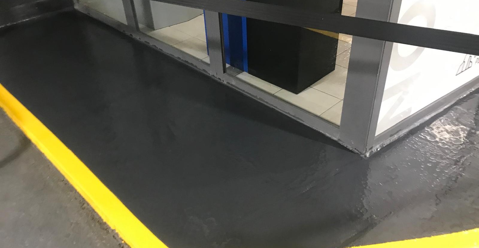 Dark coated commercial floor perimeter with bright yellow safety line